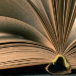 Open Book Displaying Pages With Detailed Texture And Warm Lighting On A Dark Surface